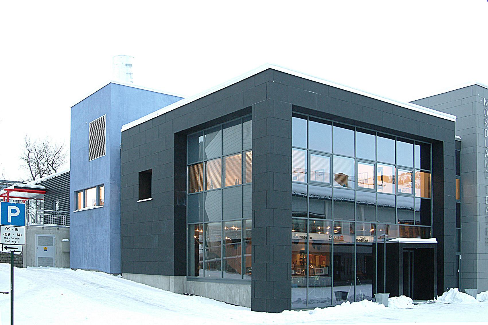 Et mørkt næringsbygg med store vinduer i snø